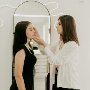 Two women standing while one does a cosmetology treatment on the other in Texas