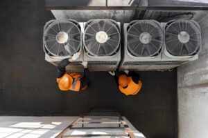 Overhead view of two men working on a large rooftop air conditioning system.