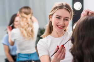 A blonde woman providing cosmetology service to another woman